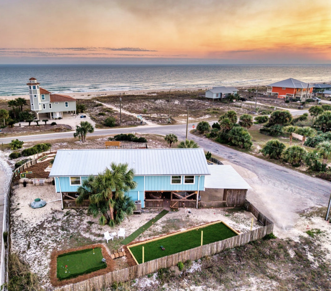 Beachfront property featuring putting green and ocean views at sunset.