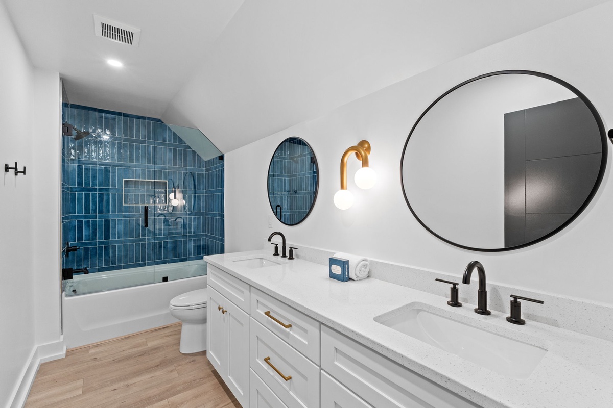 Picture yourself stepping into this serene sanctuary. Gleaming white vanities, stunning blue subway tile, and elegant round mirrors create your personal spa retreat after adventurous days.