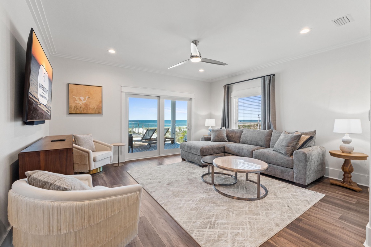 Sink into plush seating and gaze at stunning ocean views through your private glass doors. This bright, beach-inspired living room invites you to unwind in coastal elegance.