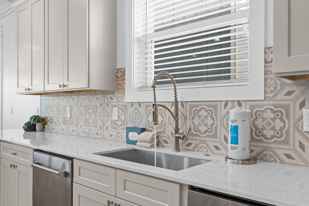 Picture yourself preparing meals in this bright, well-appointed kitchen featuring elegant patterned tile backsplash, gleaming quartz counters, and modern appliances that make cooking a pleasure.