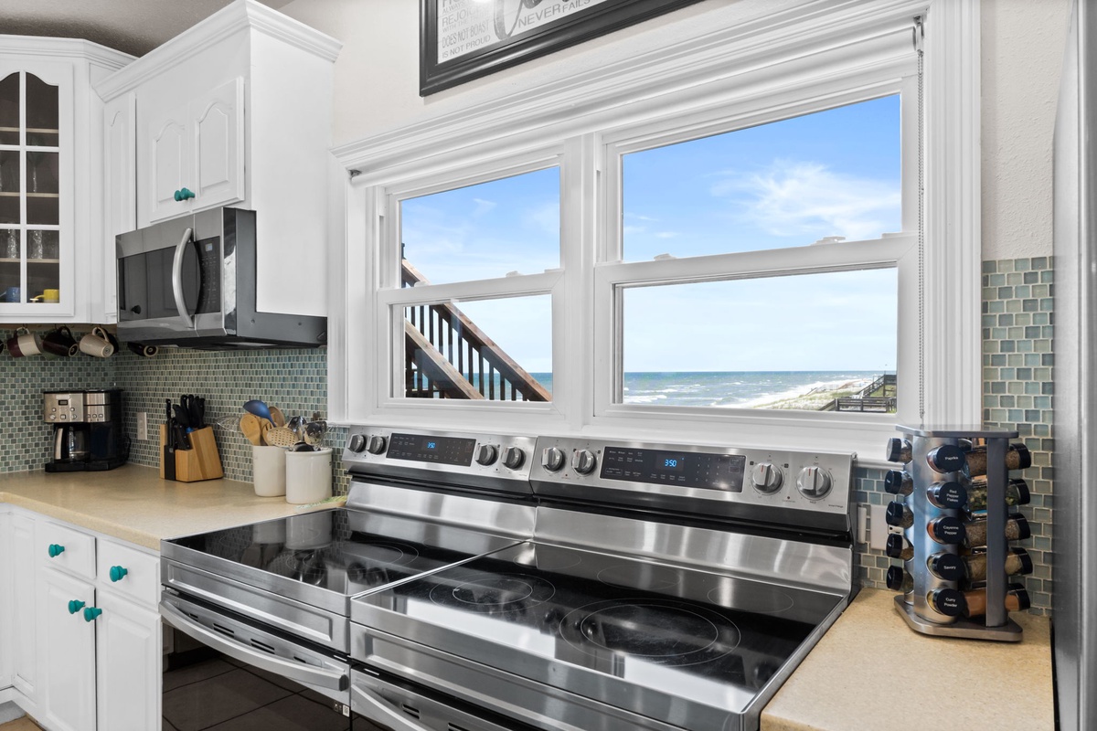 The sparkling blue ocean stretches endlessly beyond these kitchen windows, promising unforgettable mornings as you sip coffee while waves roll across the sandy shore.