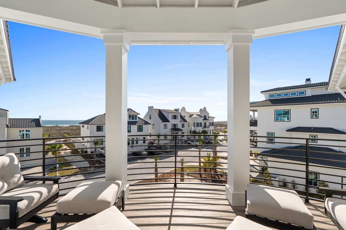 Relax in your private covered balcony with comfortable seating while enjoying panoramic views of the coastal neighborhood and distant ocean glimpses.