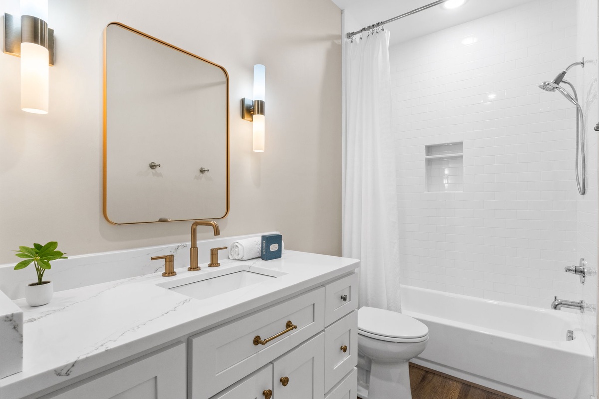 Step into your elegant bathroom featuring a marble vanity, brass fixtures, and a relaxing tub-shower combo for a luxurious start to your day.