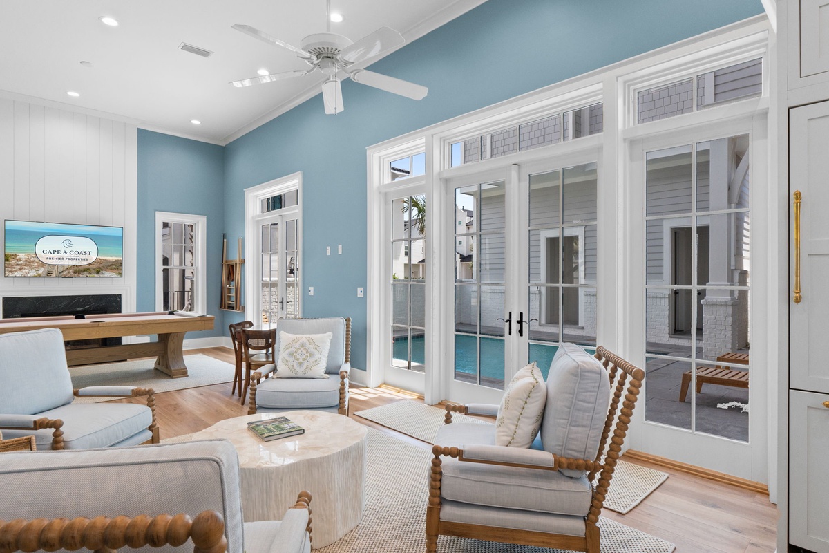 Step into your serene coastal retreat where soft blues meet warm woods, inviting you to relax. French doors frame your private pool, while plush seating and a ceiling fan promise ultimate comfort.
