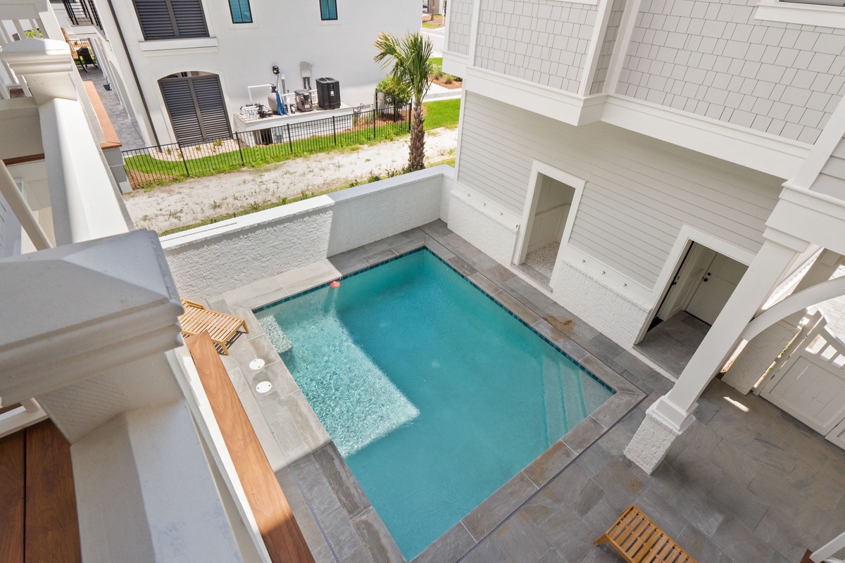 Aerial view of a private courtyard pool surrounded by modern white architecture, elegant tiling, and tropical landscaping—a serene retreat at the heart of the property.