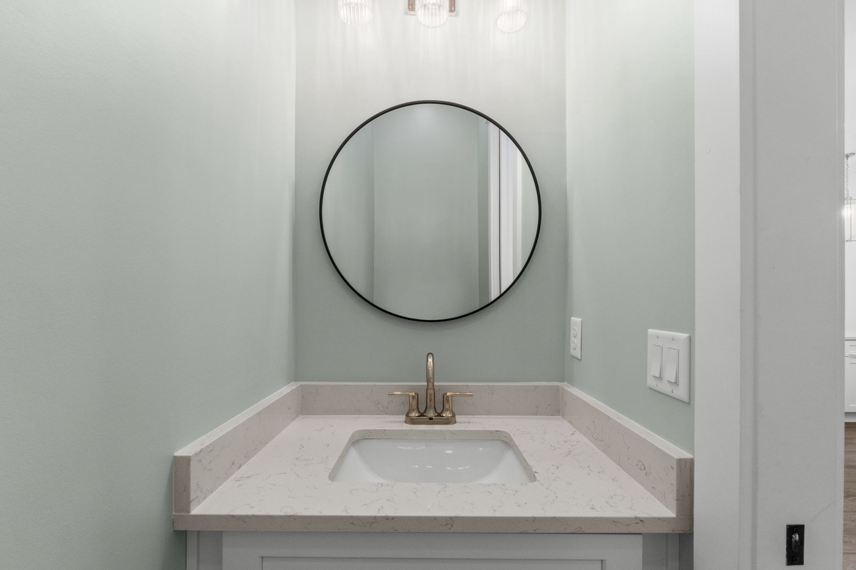 Refresh in your elegantly appointed bathroom featuring a sleek round mirror and gleaming fixtures that set the tone for relaxation.