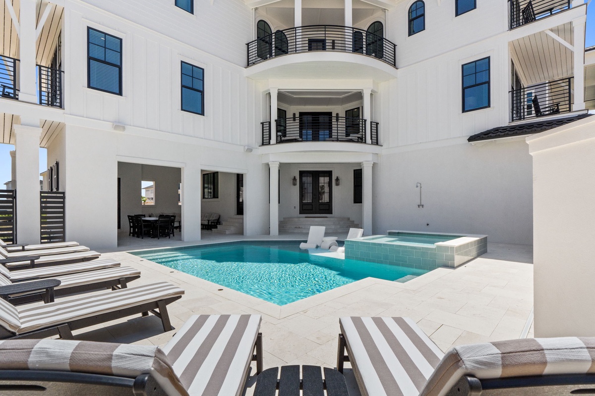 Lounge poolside in your private oasis, where sun-soaked relaxation meets elegant coastal architecture. The sparkling pool and hot tub await beneath your spacious balconies.