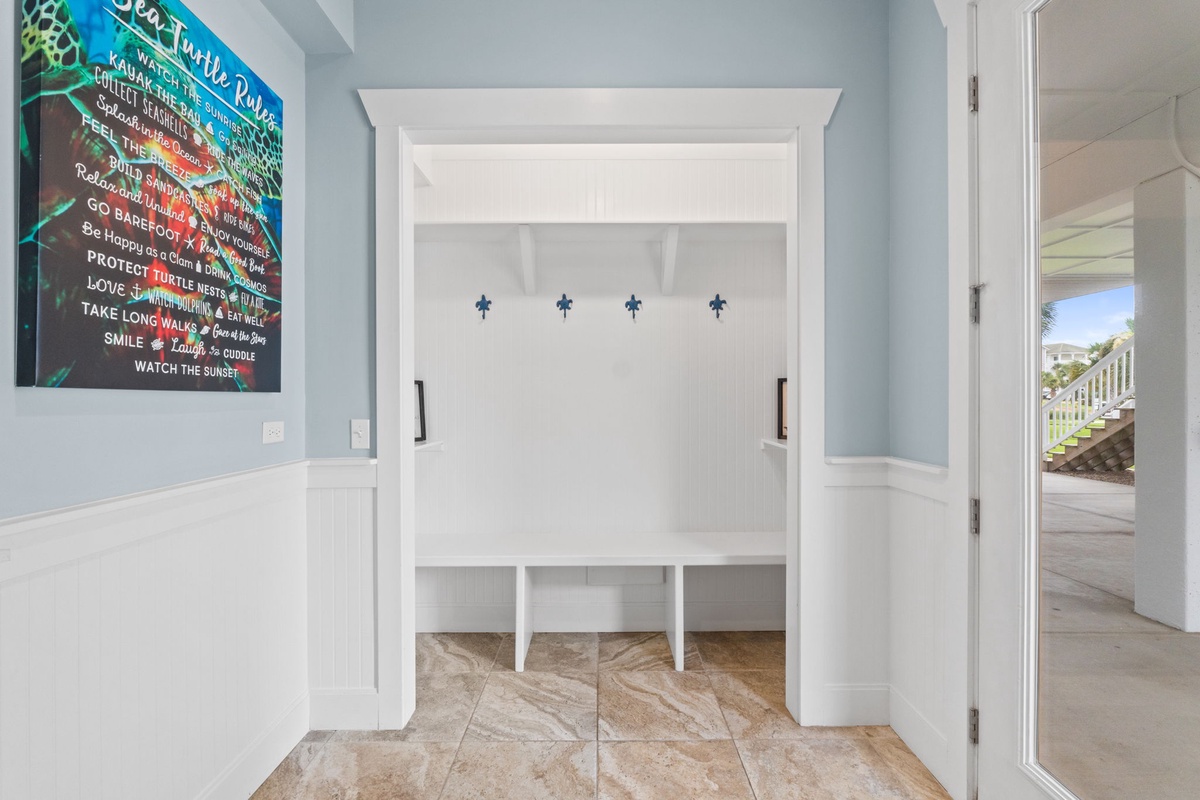 Fresh coastal vibes welcome you at the entryway with custom cubbies for your beach gear and a fun turtle-themed sign setting the vacation mood.