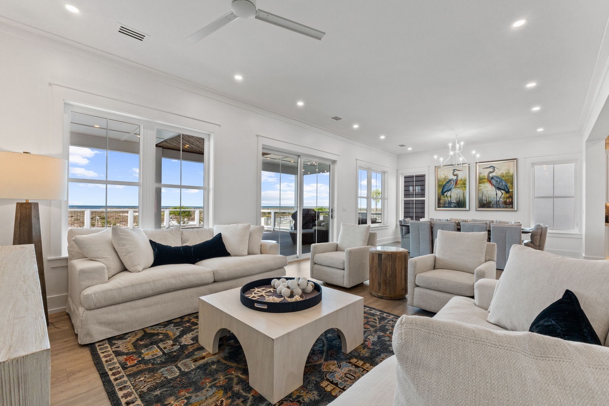 Relax in your stylish living room with plush seating, coastal artwork, and bright windows that fill the space with natural light.