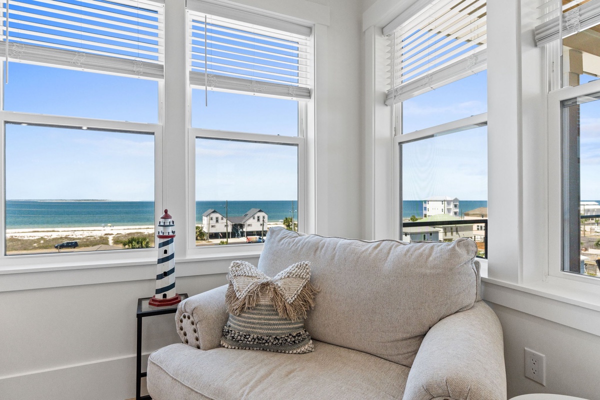 Sink into this cozy window nook with breathtaking ocean views, where gentle sea breezes and nautical touches create your perfect seaside retreat.