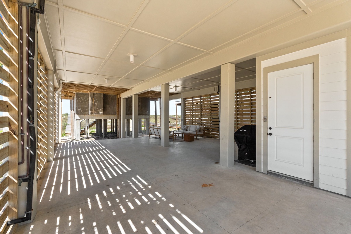 A spacious covered outdoor area with modern slatted screens filters natural light, creating inviting shadow patterns. Perfect for relaxing while taking in the scenic surroundings.
