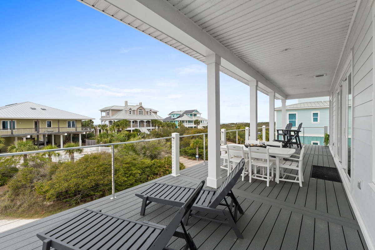 Spacious covered deck with coastal views of neighboring beach homes and lush vegetation.