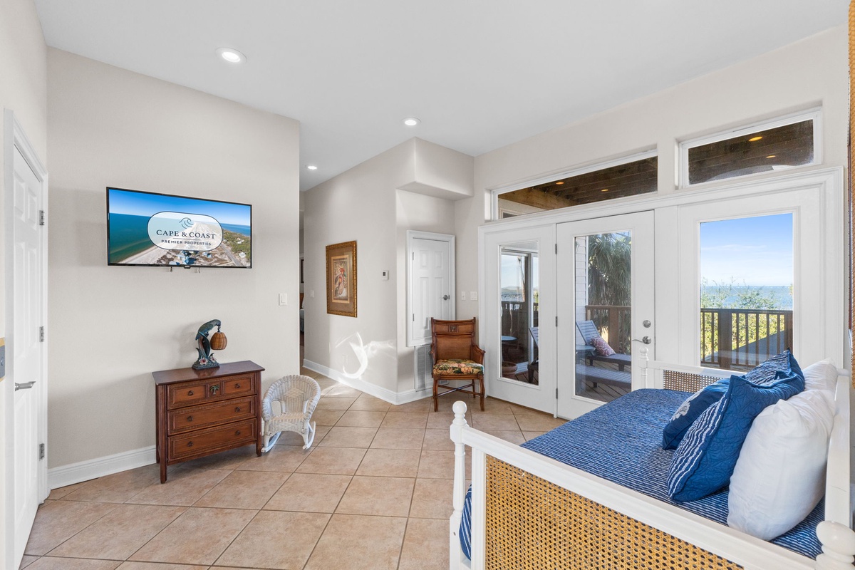 Wake up to ocean views streaming through your private balcony doors in this serene bedroom retreat with coastal charm.