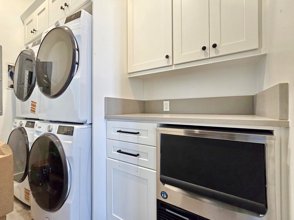 Your laundry stays effortless with this well-appointed utility room featuring stacked washer and dryer plus built-in storage.