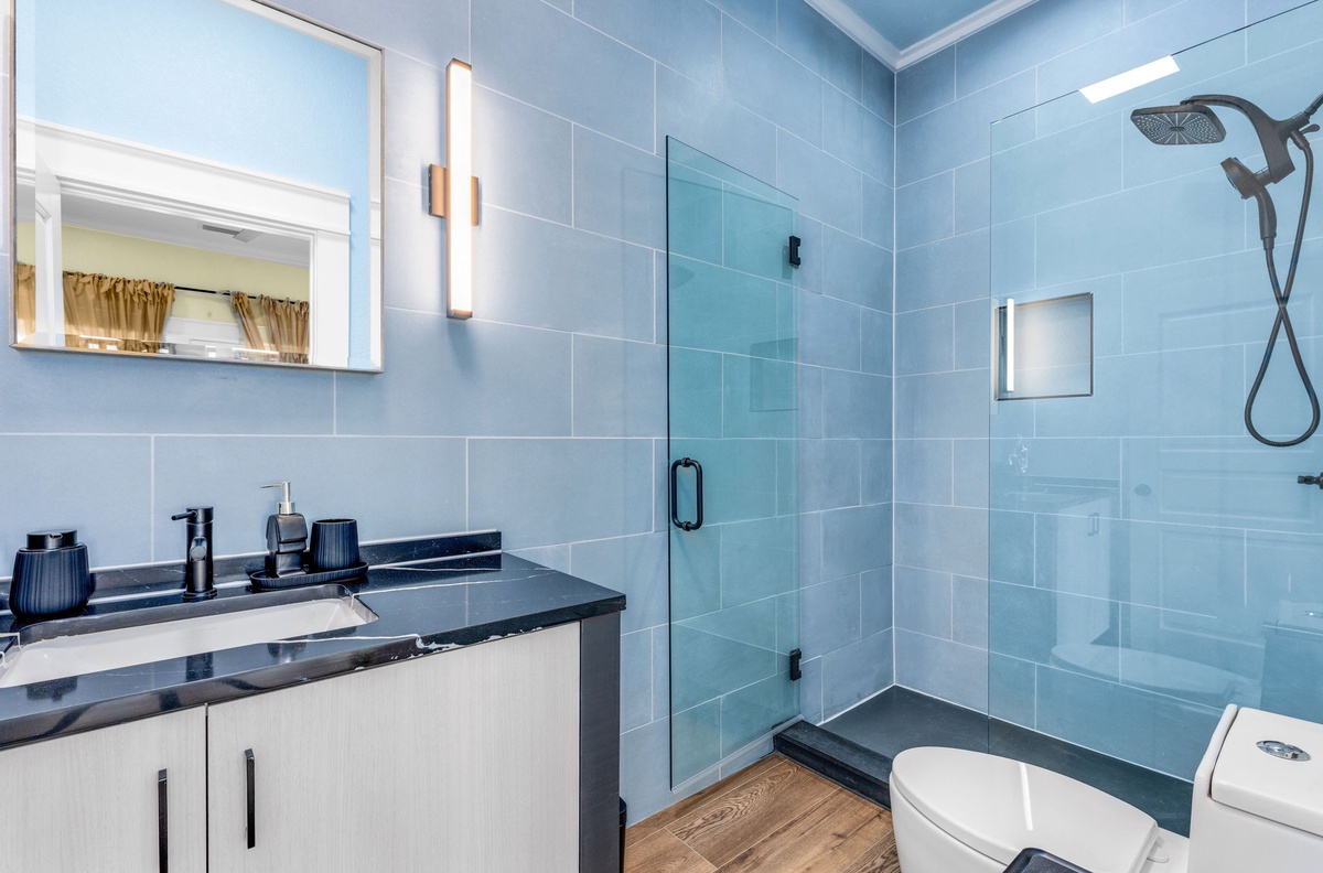 Unwind in your sleek bathroom with modern finishes, rainfall shower, and calming blue tiles.