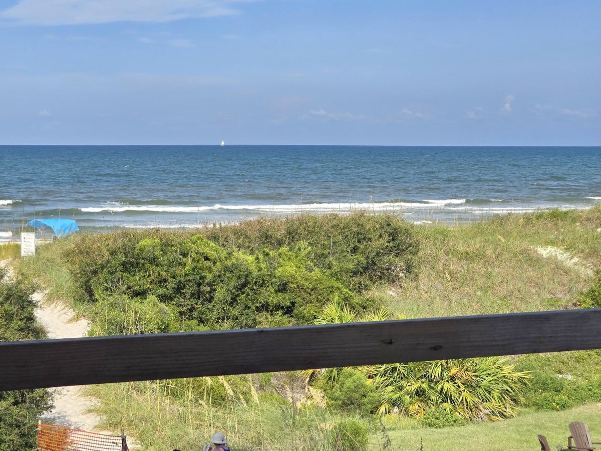 The property overlooks tranquil coastal scenery with sandy shores and natural dunes framed by a gentle horizon.