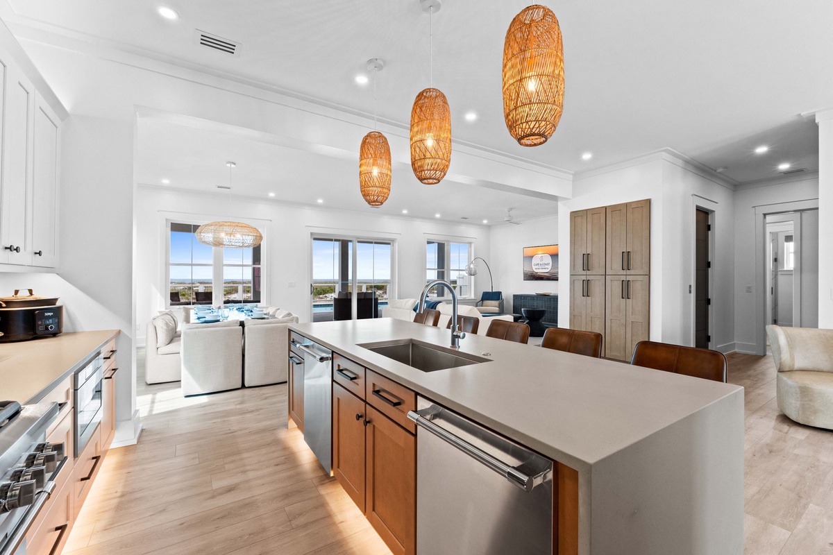 Step into this stunning open-concept space where natural light floods through large windows, warm woven pendant lights add coastal charm, and a chef-ready kitchen flows into inviting living and dining areas perfect for gatherings.