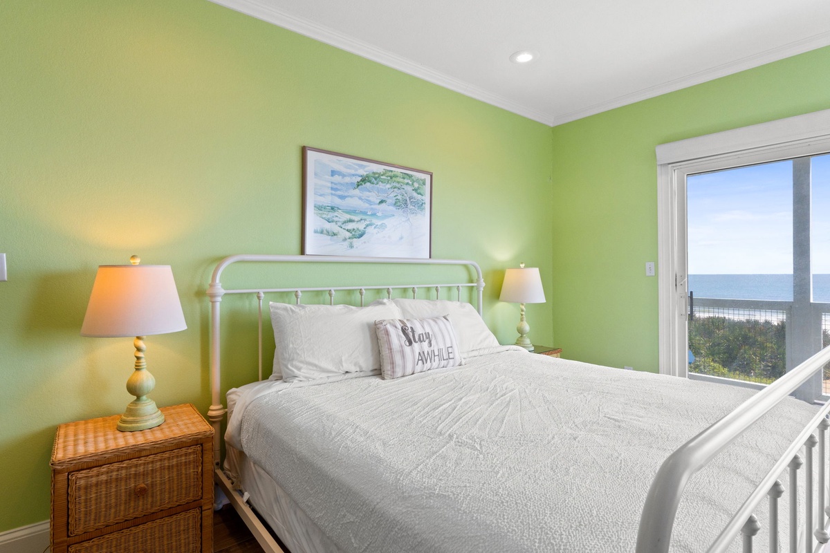 Wake up to stunning ocean views from your cozy coastal bedroom, where soft green walls and natural light create the perfect seaside retreat.