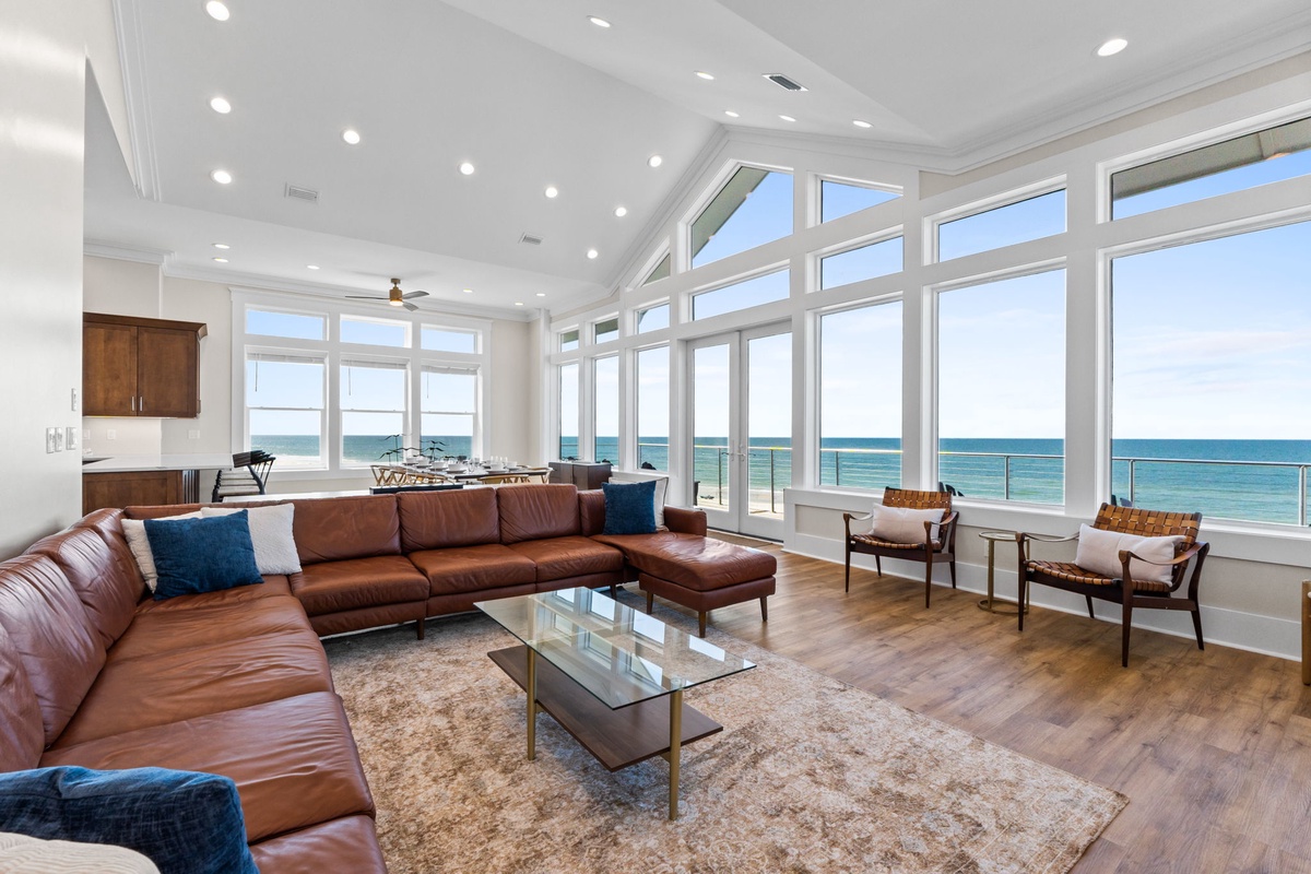 Relax in your stunning oceanfront living space with floor-to-ceiling windows showcasing breathtaking sea views and luxurious leather seating.