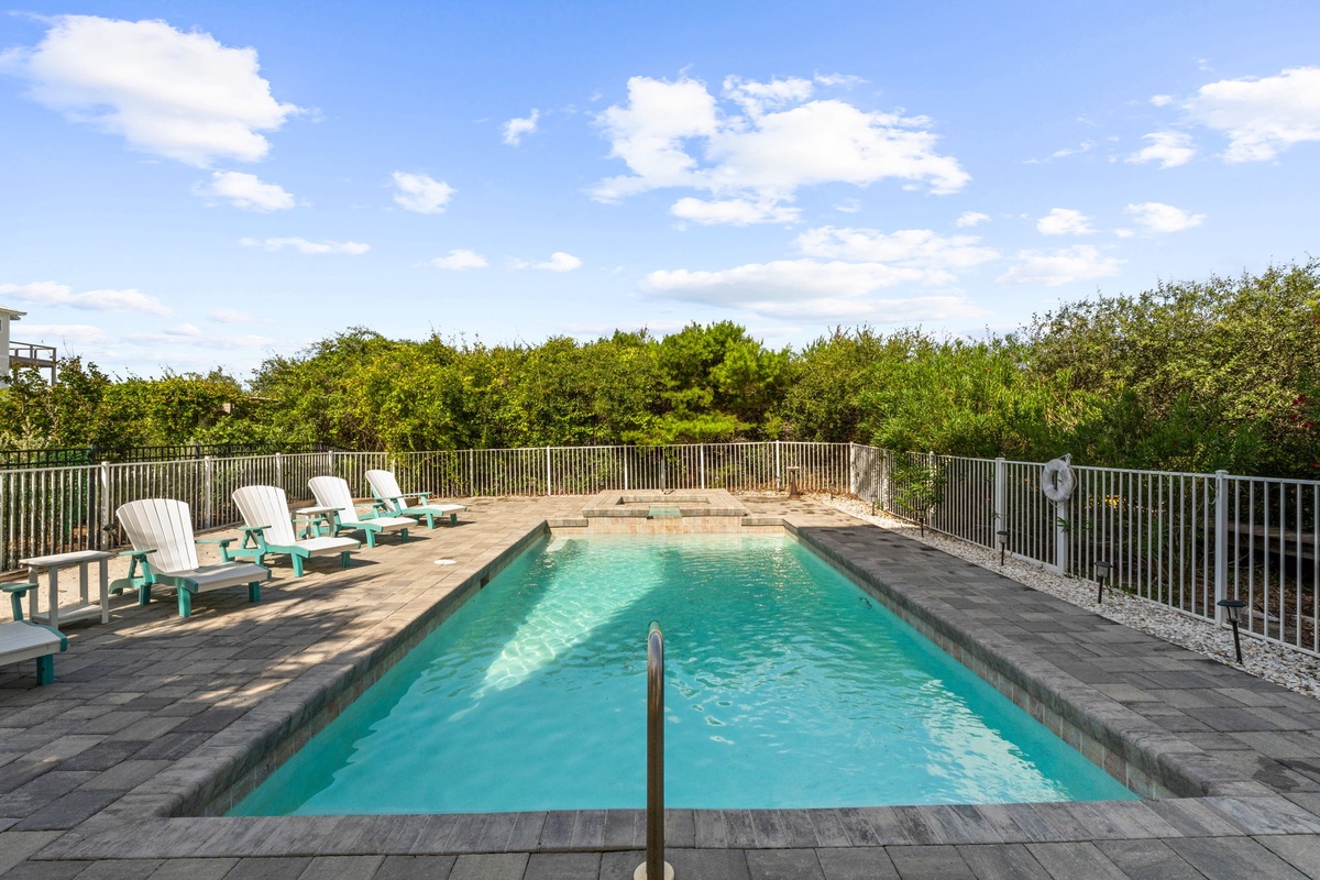 A sparkling pool surrounded by comfortable loungers creates your perfect outdoor retreat, framed by lush greenery and open skies for peaceful relaxation.