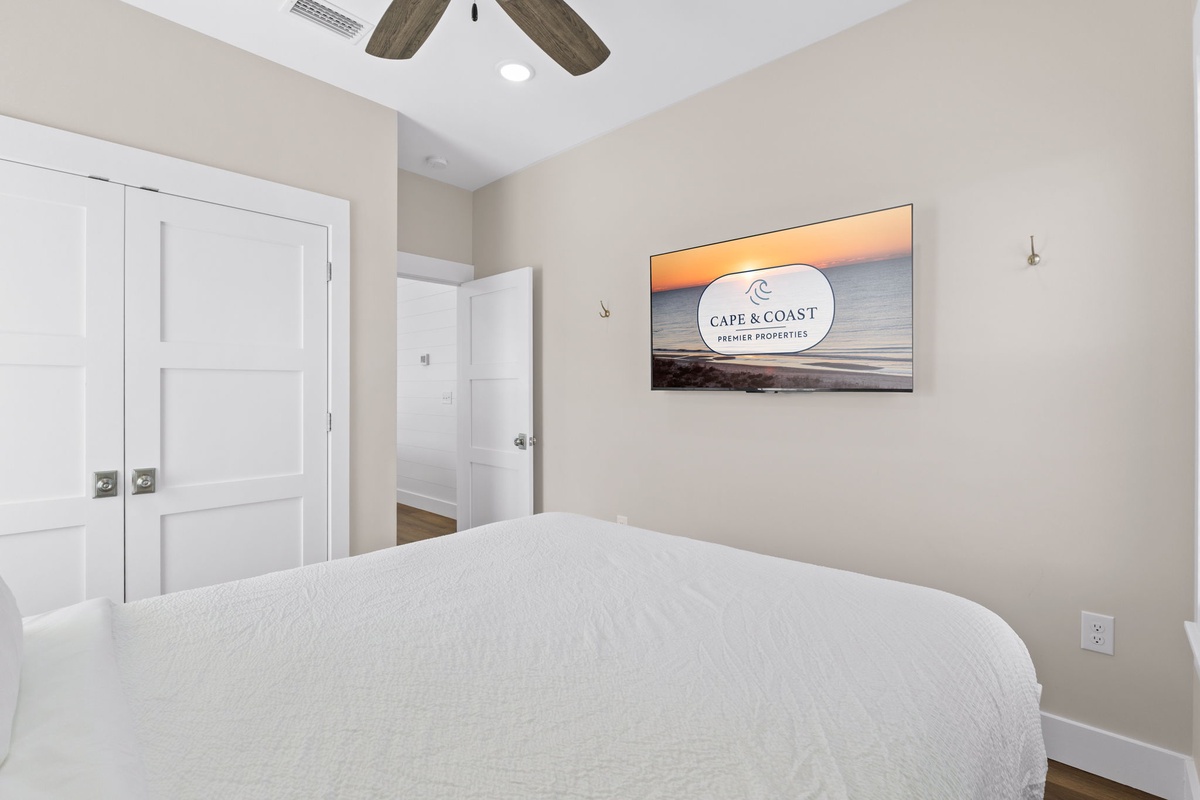 Drift off in your peaceful bedroom with crisp linens, warm coastal artwork, and rustic ceiling beams creating the perfect retreat atmosphere.