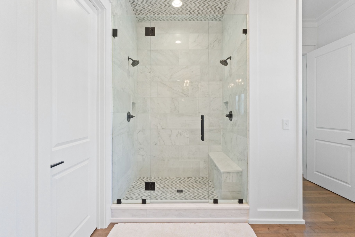 Step into your luxurious dual-head shower with marble walls and elegant tilework—perfect for refreshing after your adventures.