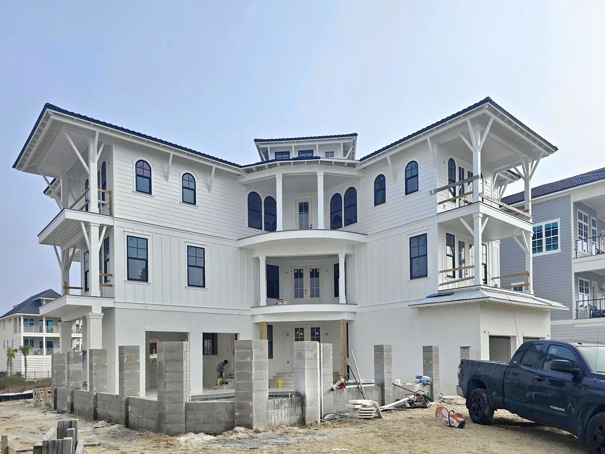 Elegant three-story coastal home nearing completion with classic white architecture and wraparound balconies in this established neighborhood.