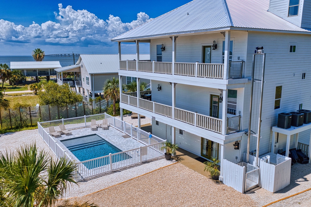 Coastal vacation home with private pool, spacious multi-level balconies, and views of the bay. Located in a quiet neighborhood near waterfront attractions and palm-lined streets.