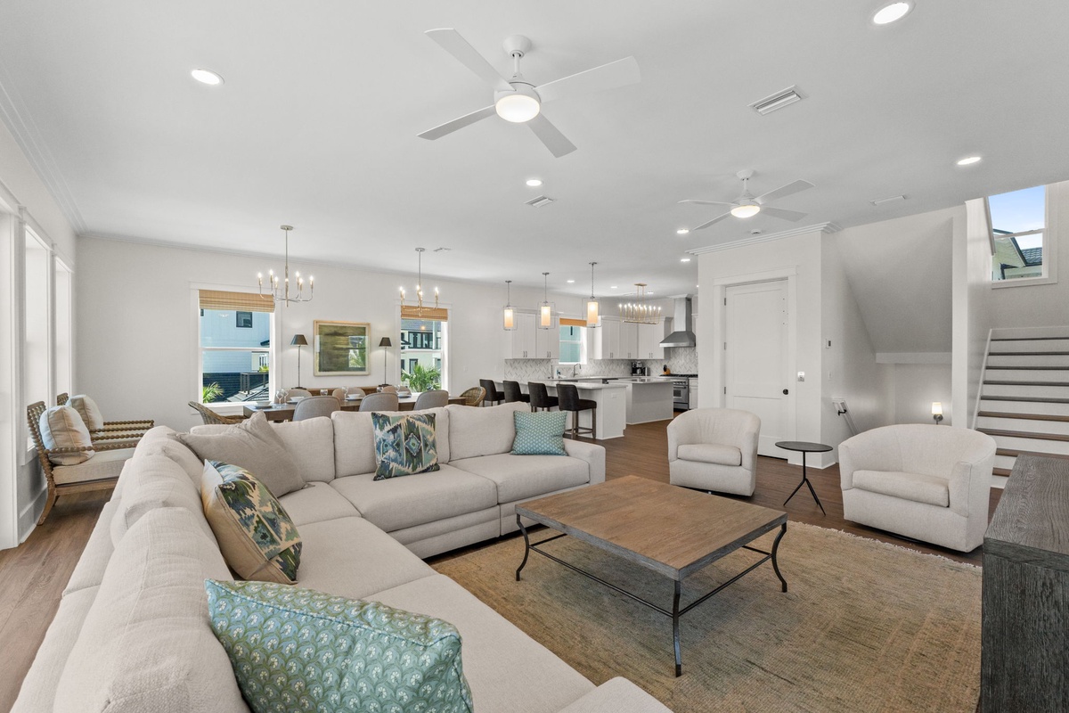 Spacious open-concept living area with natural light, plush sectional, and seamlessly integrated modern kitchen and dining spaces—perfect for gathering and relaxation.