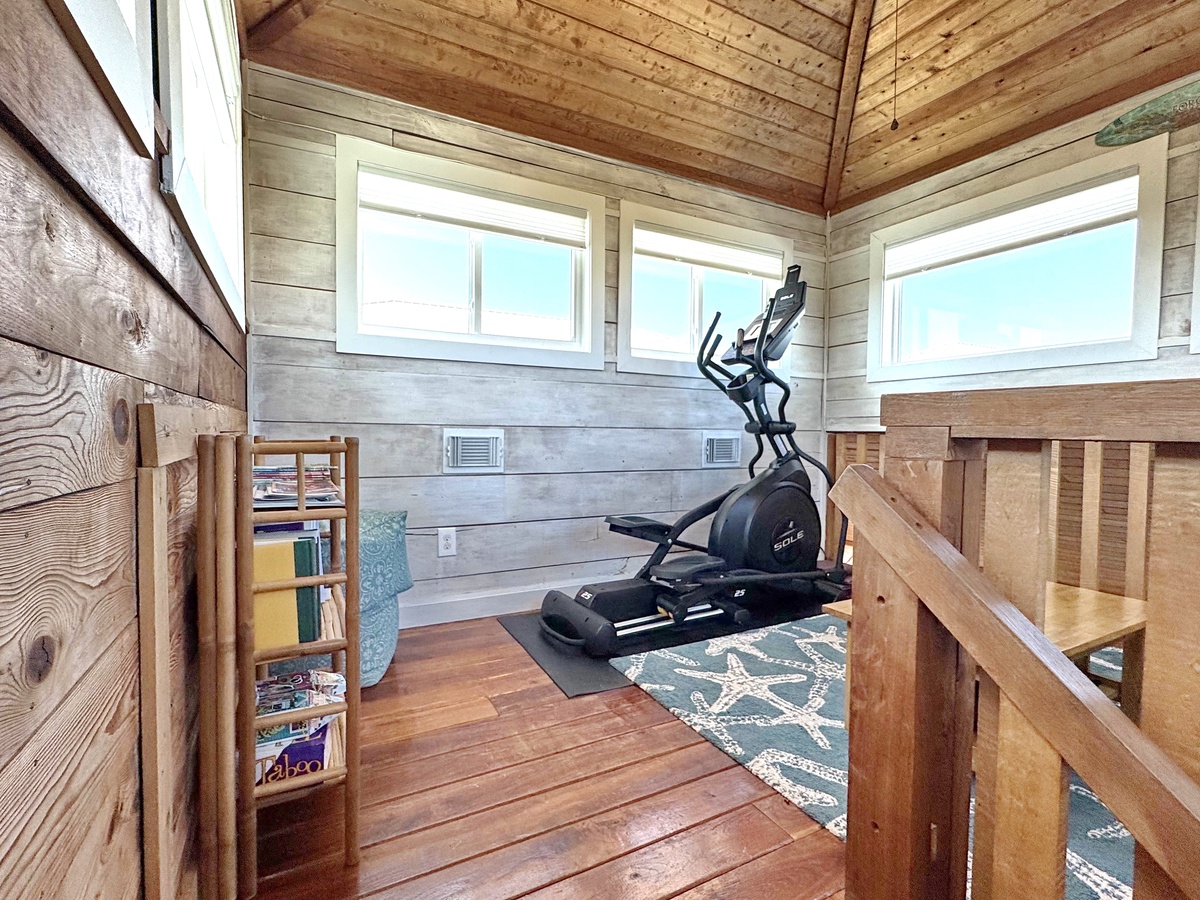 Step into your private fitness sanctuary with natural wood walls, an elliptical machine, and windows flooding the space with light for energizing workouts.