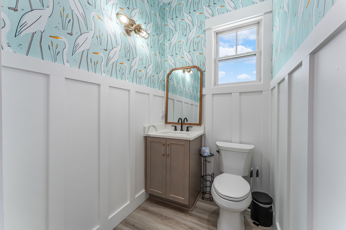 Step into this charming powder room featuring whimsical bird wallpaper and elegant wainscoting for your comfort.