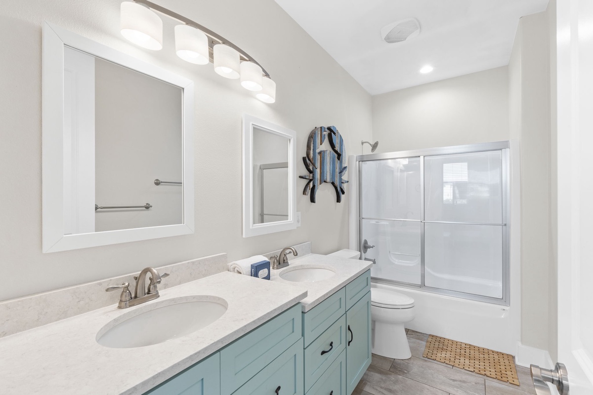 Refresh in your coastal-themed bathroom featuring dual sinks, spacious shower, and charming nautical touches that set the perfect seaside mood.