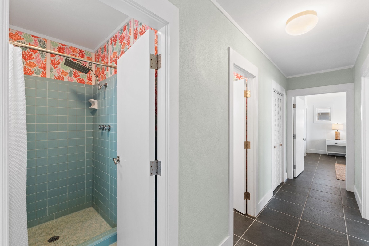 Your private bathroom features a spacious walk-in shower with calming blue tile and charming coastal wallpaper accents that bring seaside style indoors.