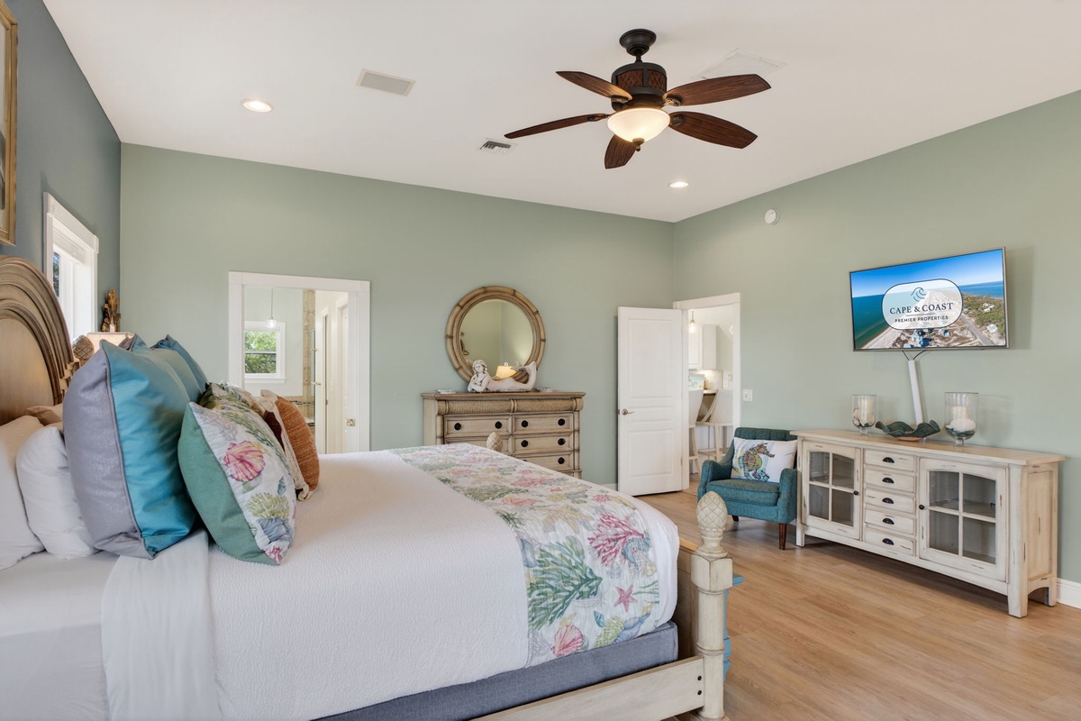 Unwind in your coastal-themed bedroom with soft sage walls, ceiling fan, and tropical bedding. The spacious layout and cheerful TV corner create perfect relaxation.