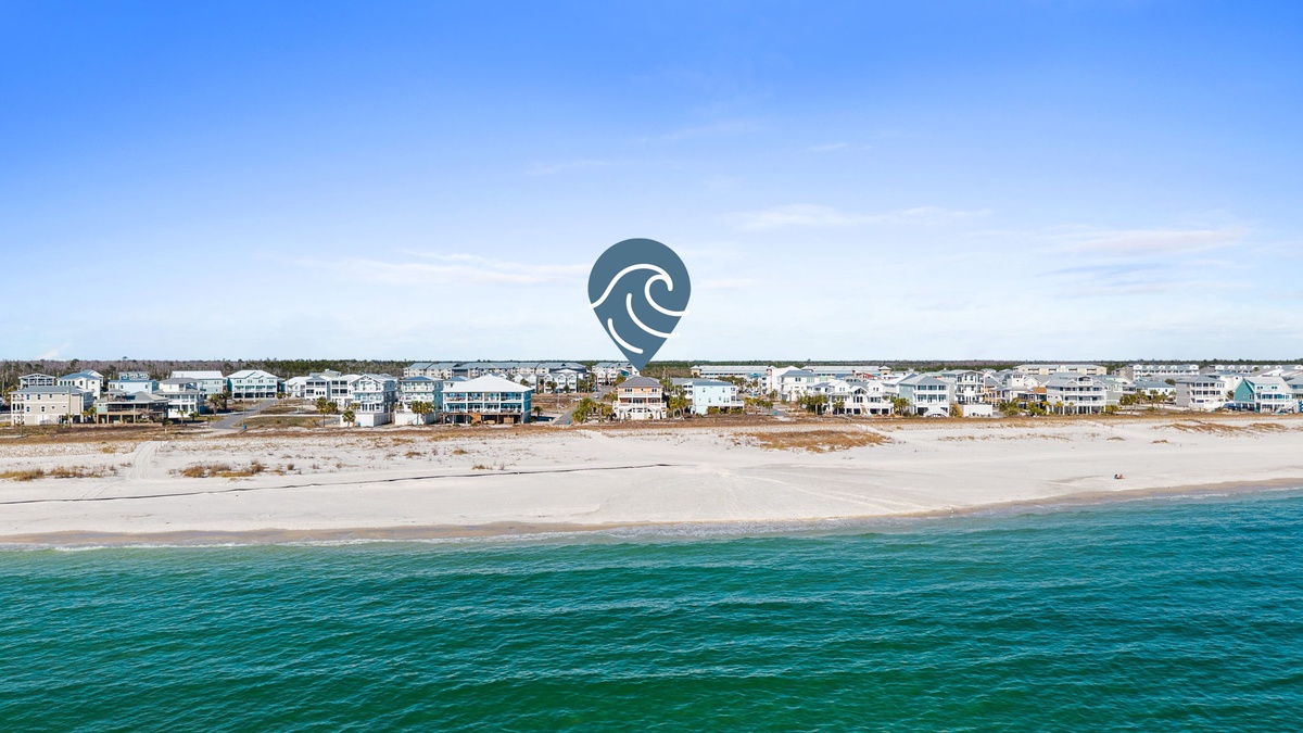 Aerial view of beachfront vacation rental community with pristine sandy shores and crystal-clear turquoise waters stretching to the horizon.