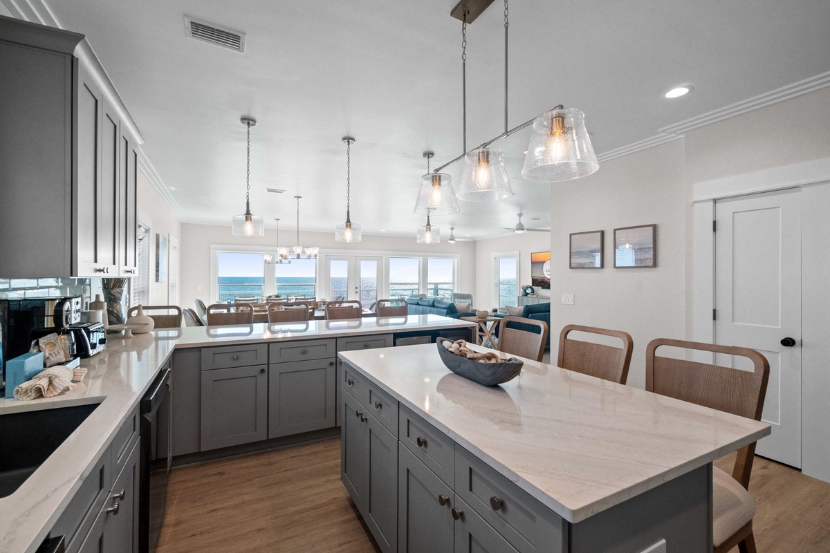 Cook with spectacular ocean views through floor-to-ceiling windows in your gourmet kitchen, complete with elegant pendant lighting and spacious island.