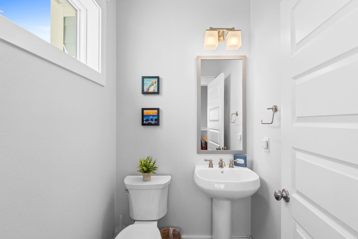 Step into your bright, modern powder room with clean white fixtures and charming coastal artwork that creates a welcoming atmosphere.