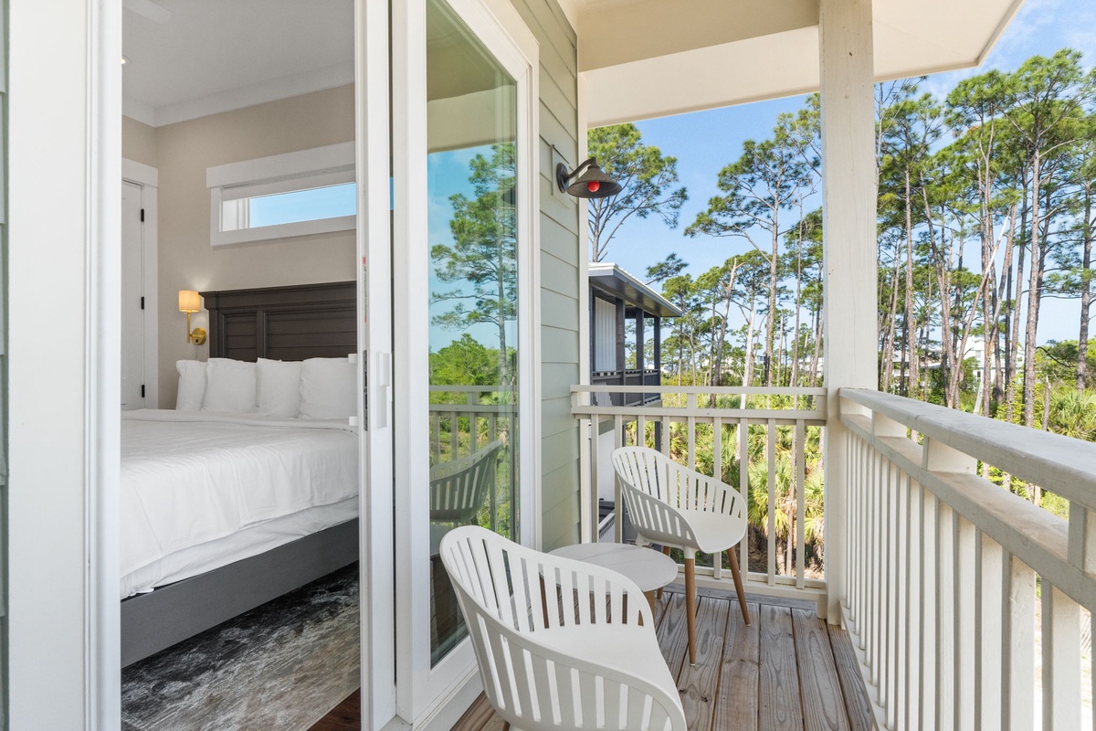 Step onto your private balcony where two comfortable chairs await your morning coffee, overlooking peaceful treetops through floor-to-ceiling windows.