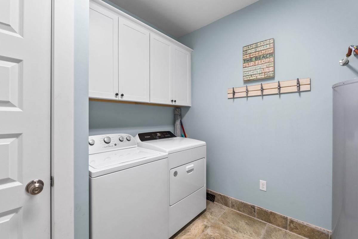 Dedicated laundry room with full-size washer and dryer, custom cabinetry, and beach-themed decor keeps your vacation wardrobe fresh and ready.