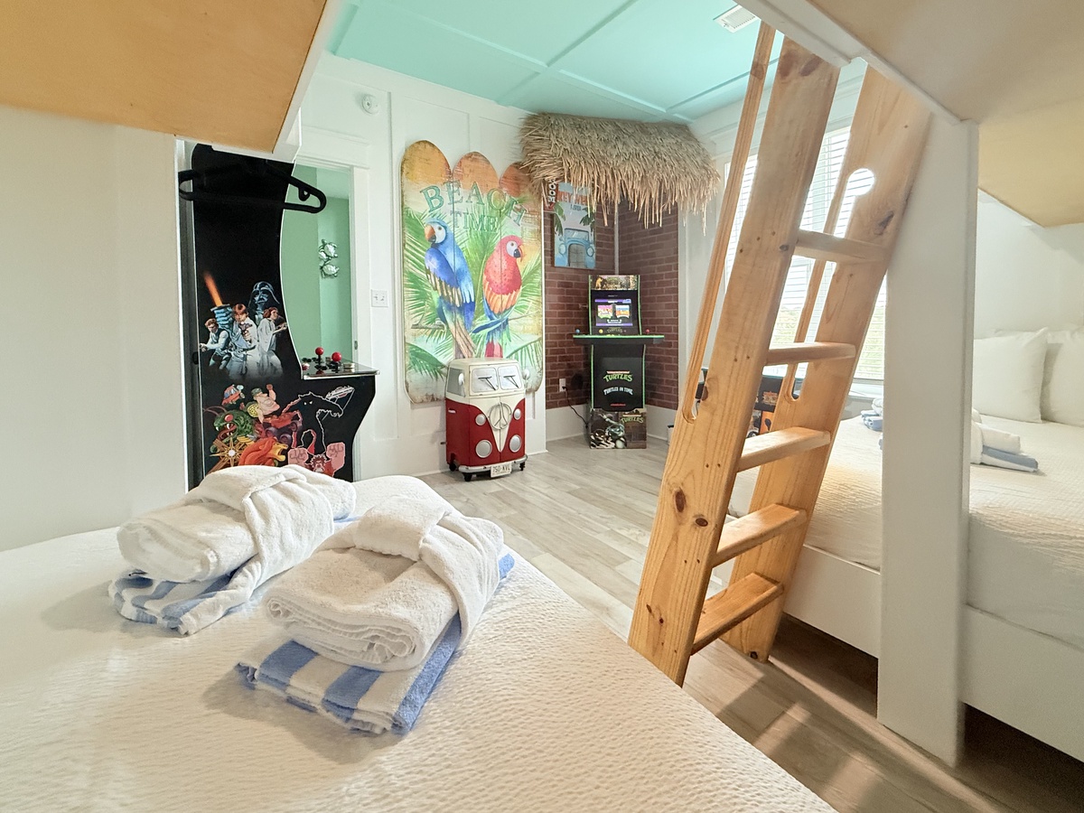 Your kids will love this tropical-themed bedroom with bunk beds, game machine, and colorful parrot artwork creating adventure vibes.