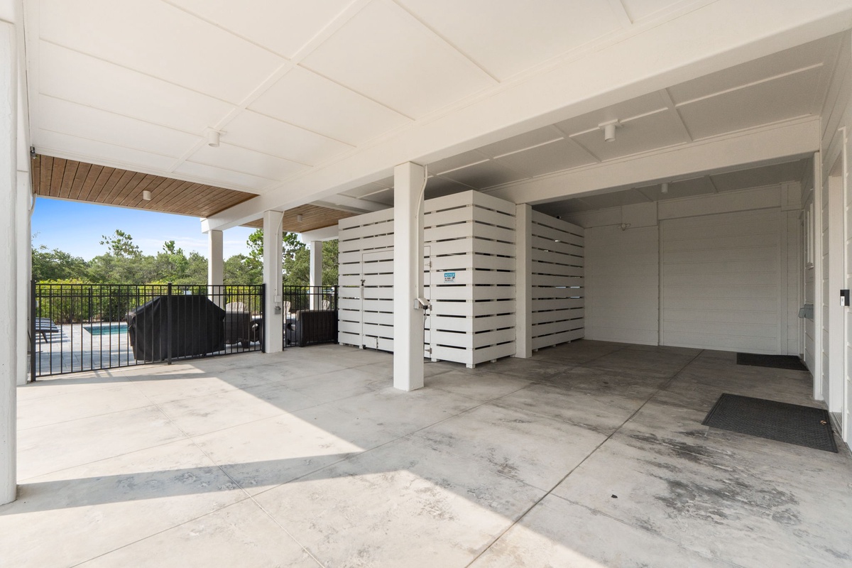 Covered parking area with secure storage panels and gated access to the pool, providing convenient shelter and organized space for your vehicles and outdoor gear.