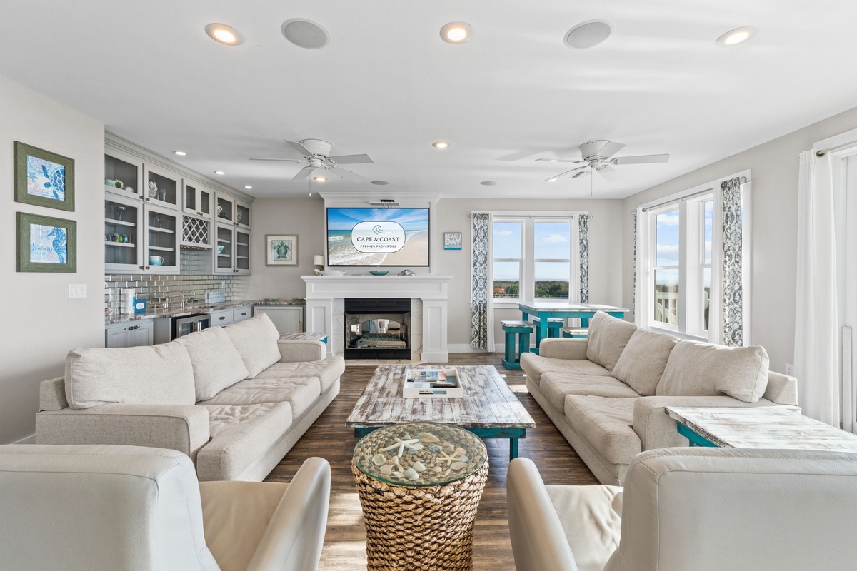 Sink into plush sectional sofas in this bright, airy living space featuring a cozy fireplace and modern entertainment setup.