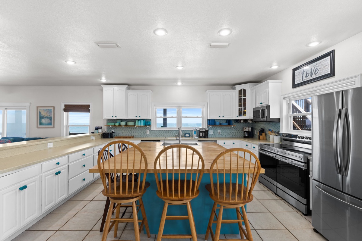 Gather around the spacious kitchen with ocean views, stainless appliances, and coastal-inspired teal accents—perfect for prepping meals and sharing stories with your crew.