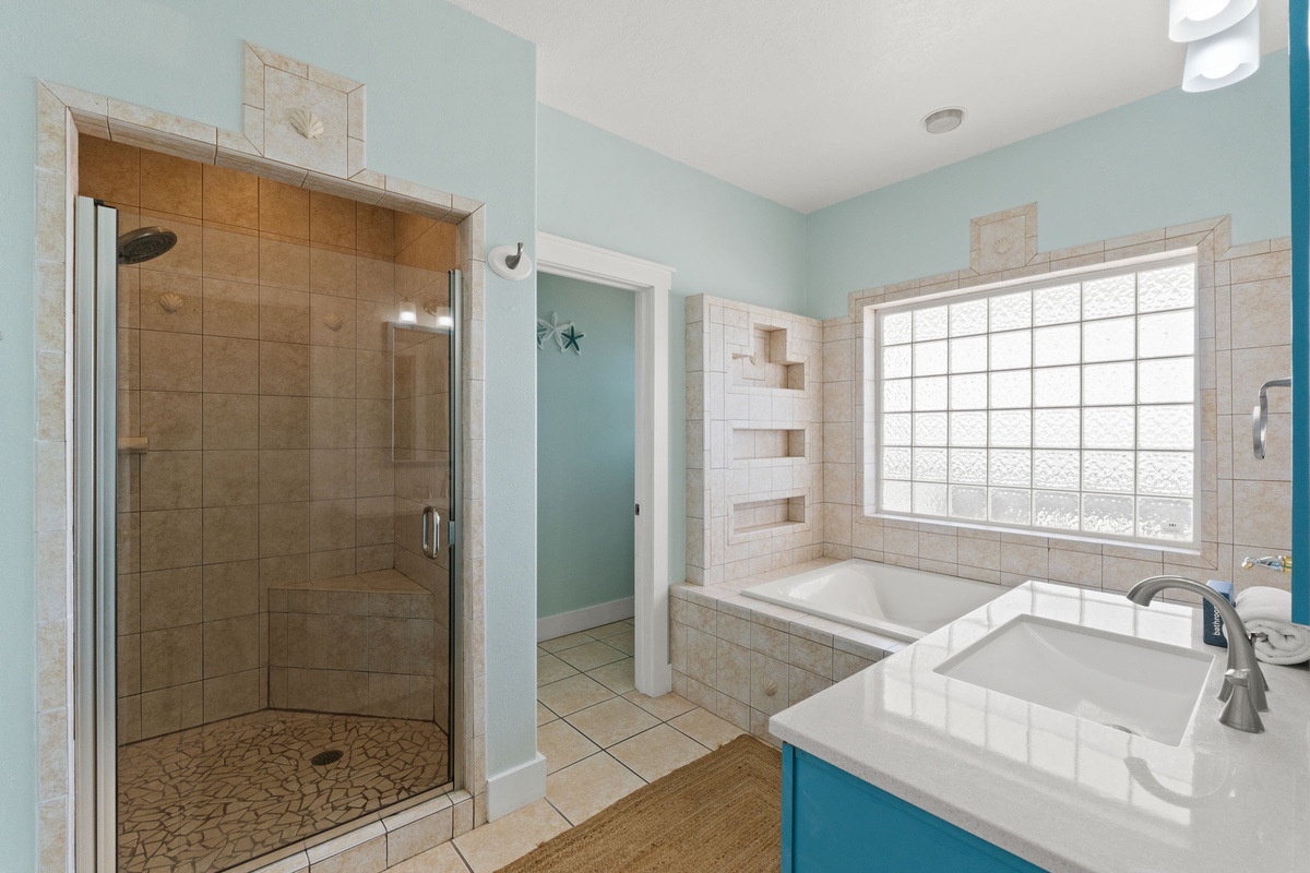 Refresh in your private spa-inspired bathroom with a spacious walk-in shower, soaking tub beneath bright natural light, and stylish coastal blue touches throughout.