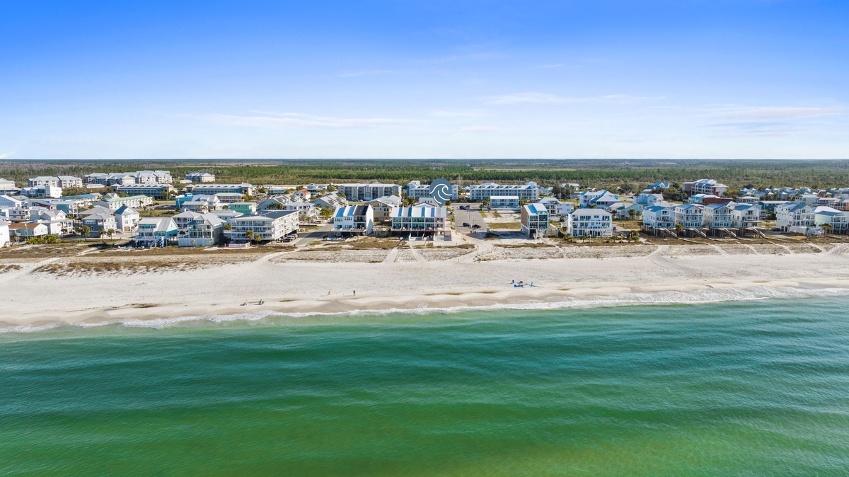 Aerial view showcases pristine beachfront with turquoise waters and coastal community development along the shoreline.