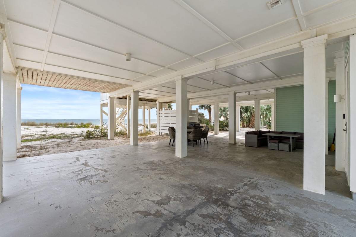 Your covered outdoor space opens to endless beach views, with dining area and lounge seating perfect for morning coffee or sunset cocktails.