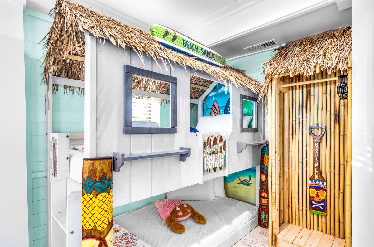 Your little ones will love this tropical beach-themed bunk bed hideaway with authentic thatched details and colorful surfboard decorations.