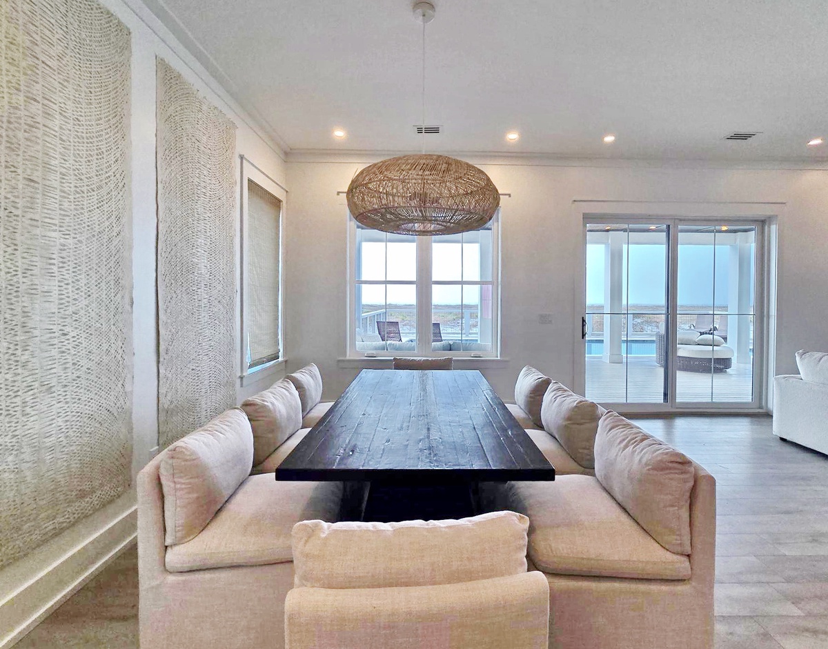 Gather around the stunning reclaimed wood table in your bright dining space, where woven textures and pool views create perfect dinner conversations.