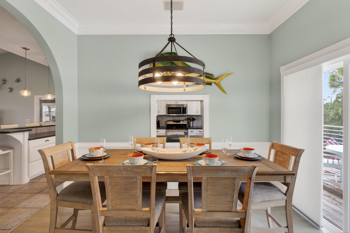 Gather around this beautiful wooden dining table where memorable meals await. The coastal-inspired chandelier and serene sage walls create the perfect atmosphere for your vacation dining.