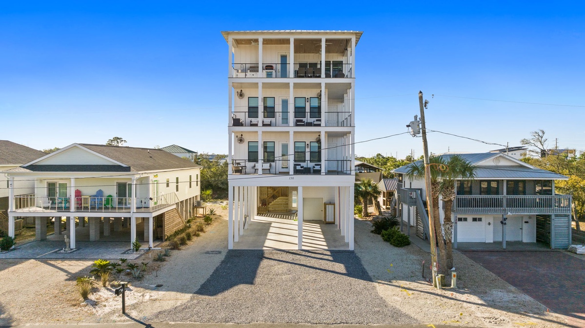 Modern beachside property featuring multiple levels with covered parking and neighboring coastal homes in a quiet residential setting.